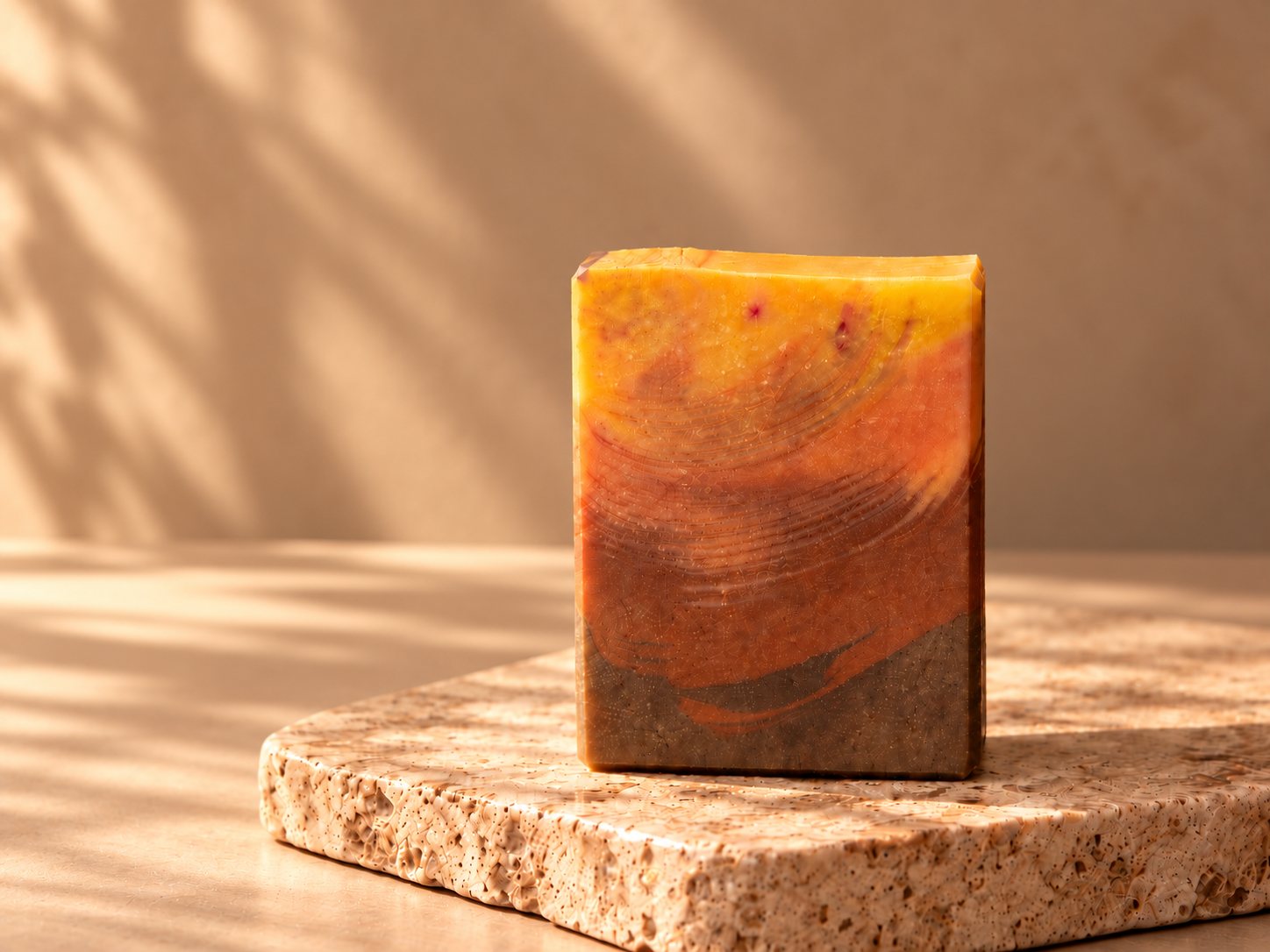 Cafuné bar poured gold to rust to chocolate, on a travertine block in warm window light